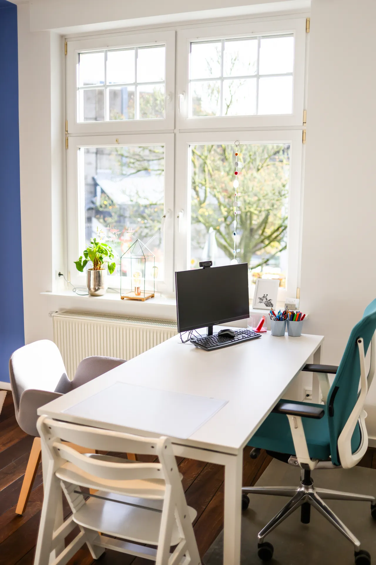 Ein Arbeitsplatz am Fenster in Therapieraum 2, mit Bildschirm, Tisch und Stühlen in Kinderhöhe