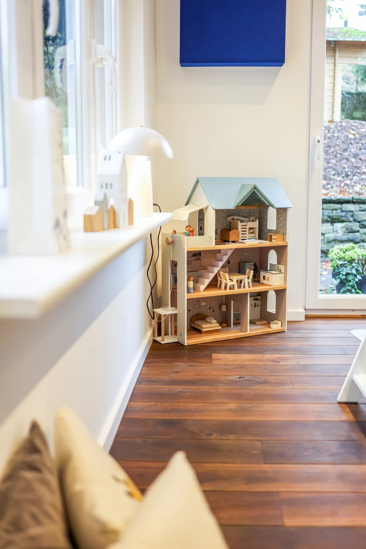 Therapieraum 4 mit Sitzecke am Fenster, Kissen und einem großen Puppenhaus aus Holz