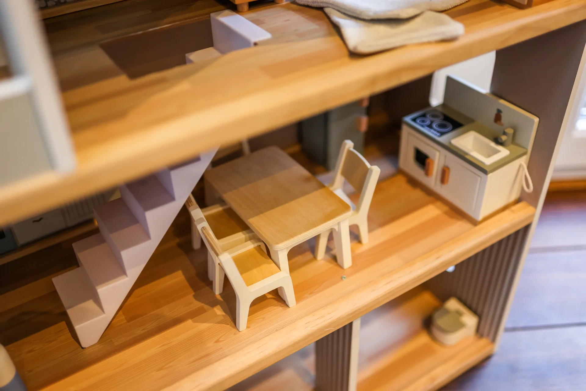 Das eingerichtete Puppenhaus aus der Nähe: Treppe, Küche und Möbel aus hellem Holz
