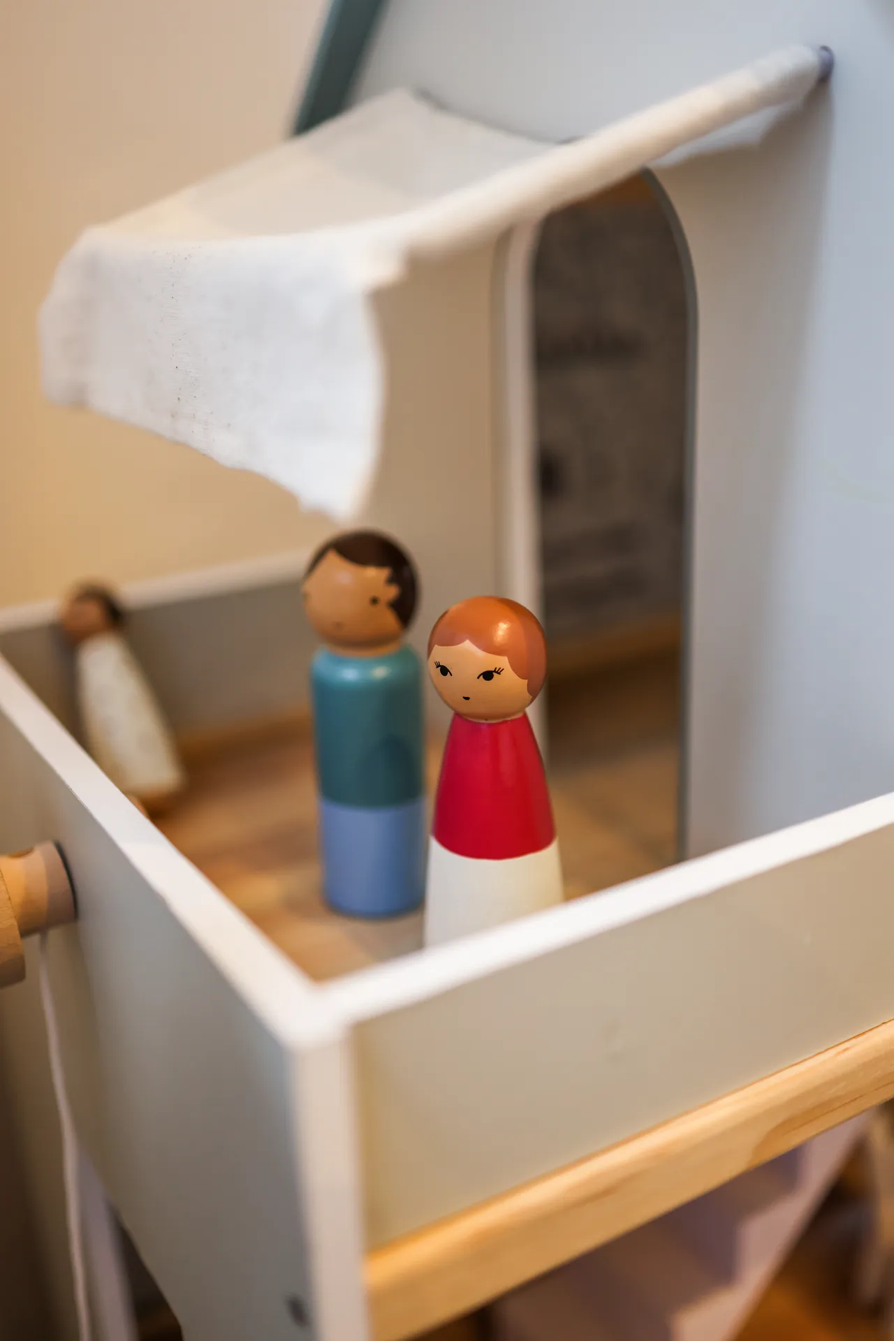 Zwei bemalte Holzfiguren stehen im obersten Stockwerk des Puppenhauses